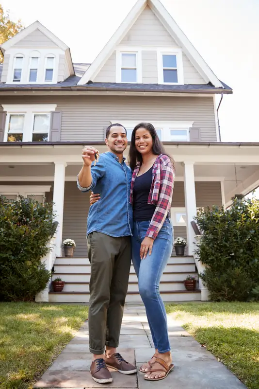 Hispanic couple embracing holding a key to their new home